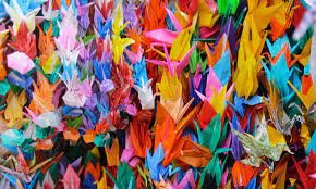 A colorful collection of folded paper cranes, origami art with various vibrant colors.