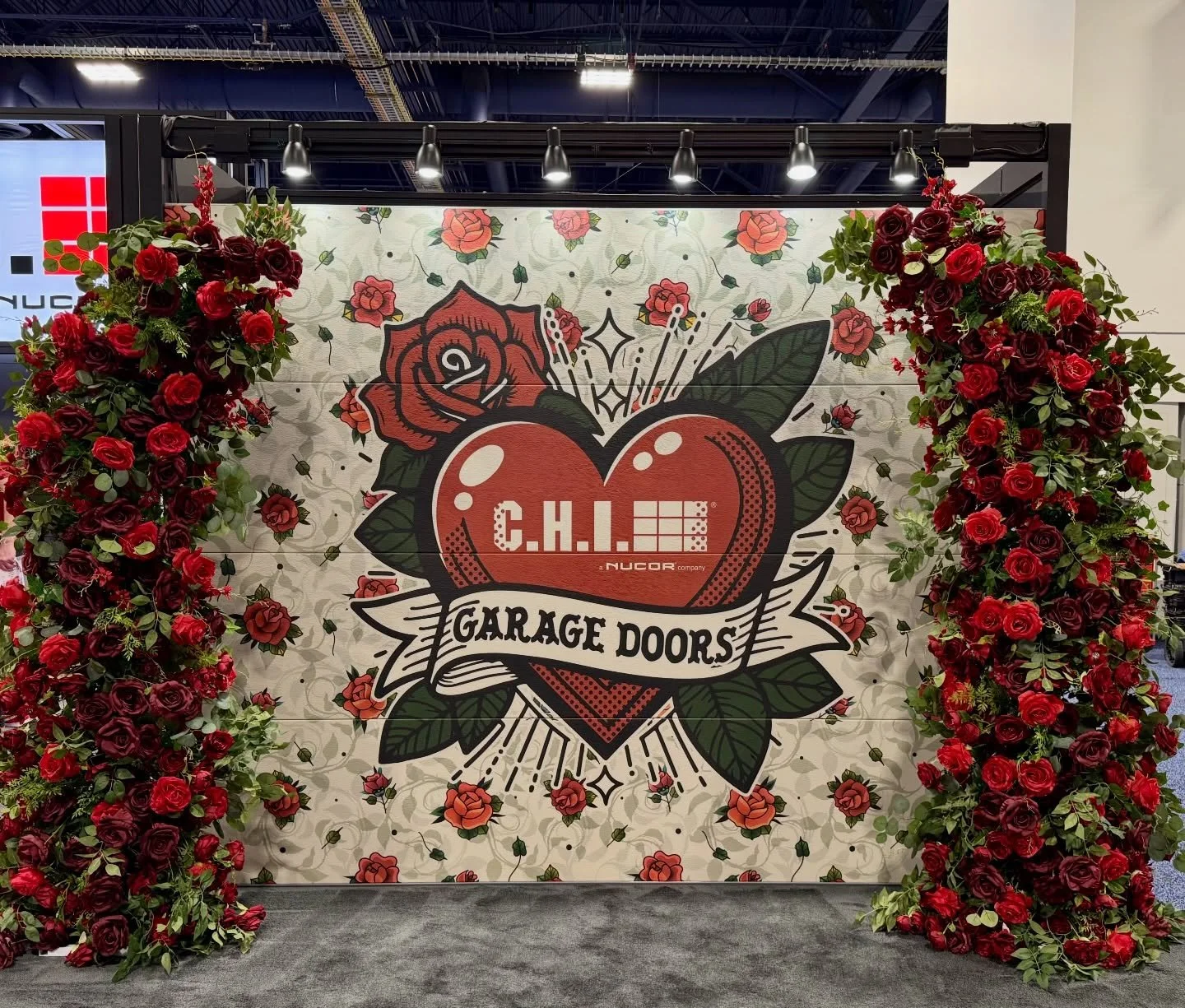 New custom Hearts Desire flower arch for Nucor custom printed garage door&rsquo;s trade show booth! 🌹 An elegant and on trend horn flower arch. Red and burgundy roses mixed with green foliage make our Hearts Desire flower arch a show stopper! Perfec