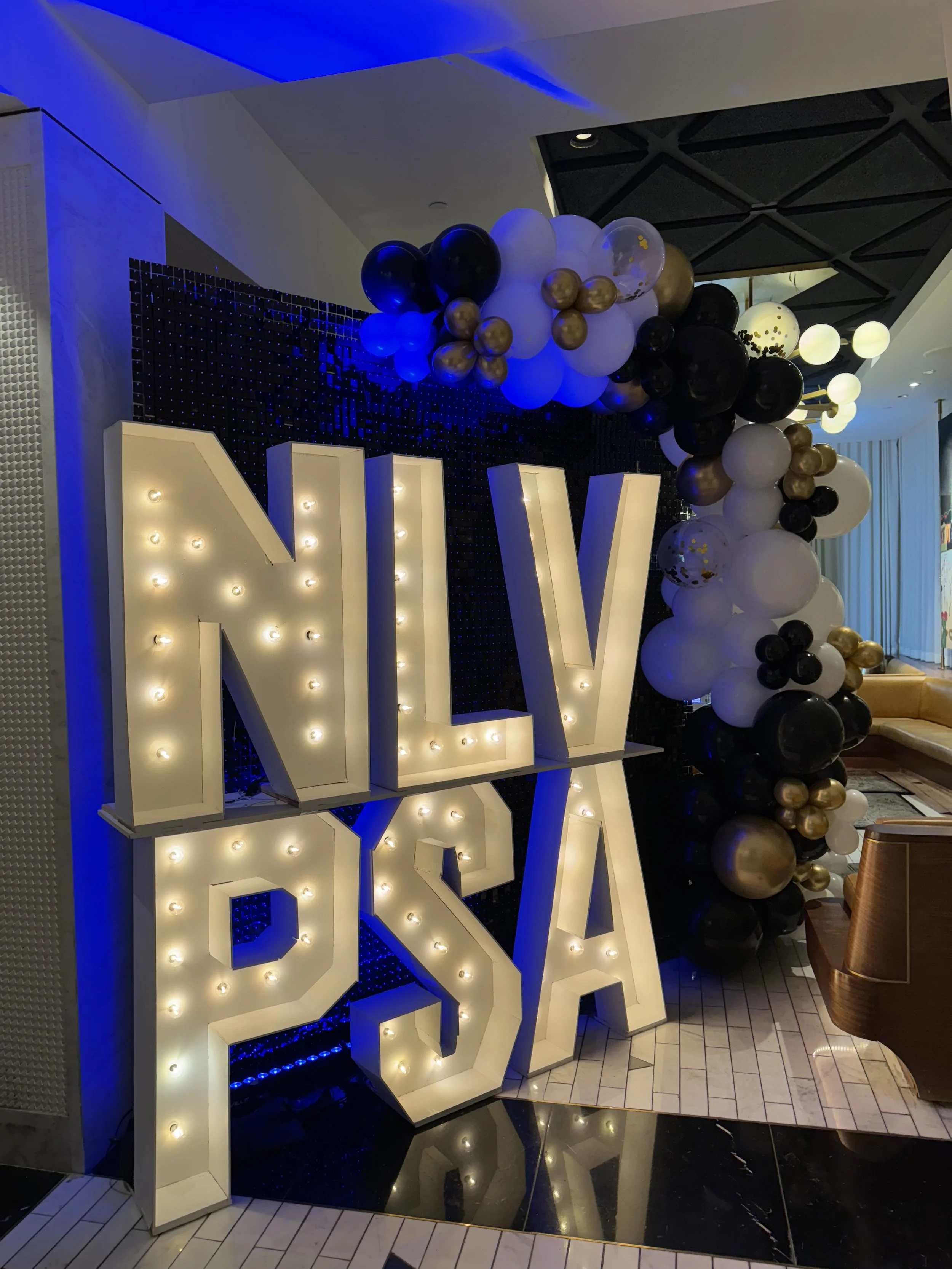 black shimmer wall with balloon garland and marquee letters Flower Walls Las Vegas