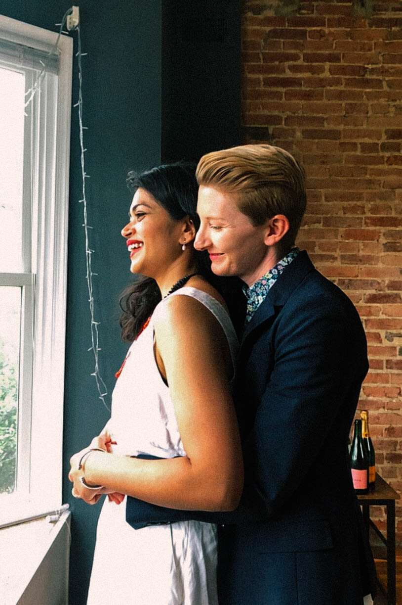 Queer couple holding each other while looking out the window in DC Shawnee Custalow Queer Wedding Photographer