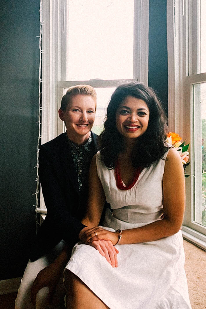 Newlywed couple smiling and posing by windows in DC Shawnee Custalow Queer Wedding Photographer