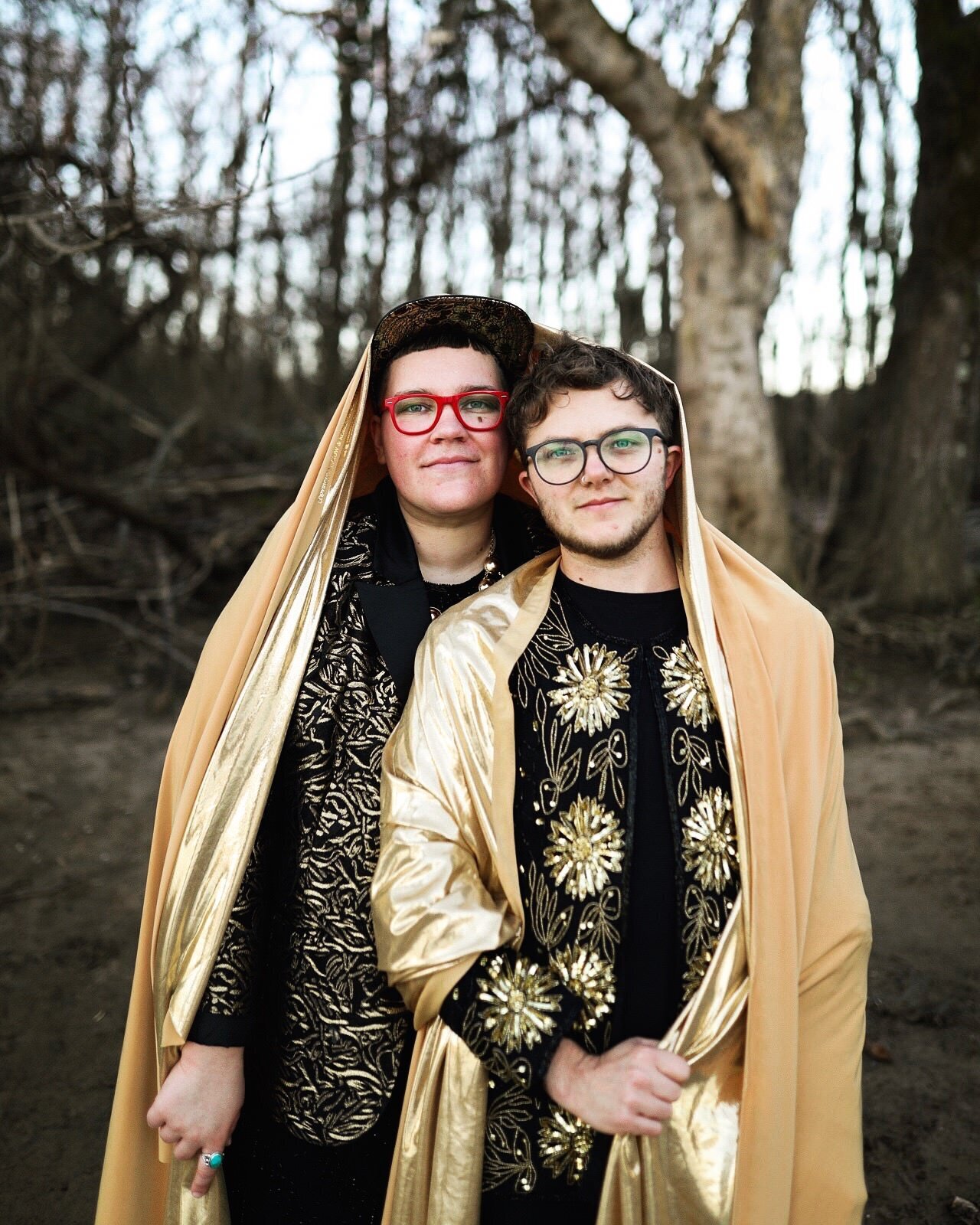 LGBTQ engaged couple draped in golden fabric and wearing back and gold in Richmond VA Shawnee Custalow Queer Wedding Photographer