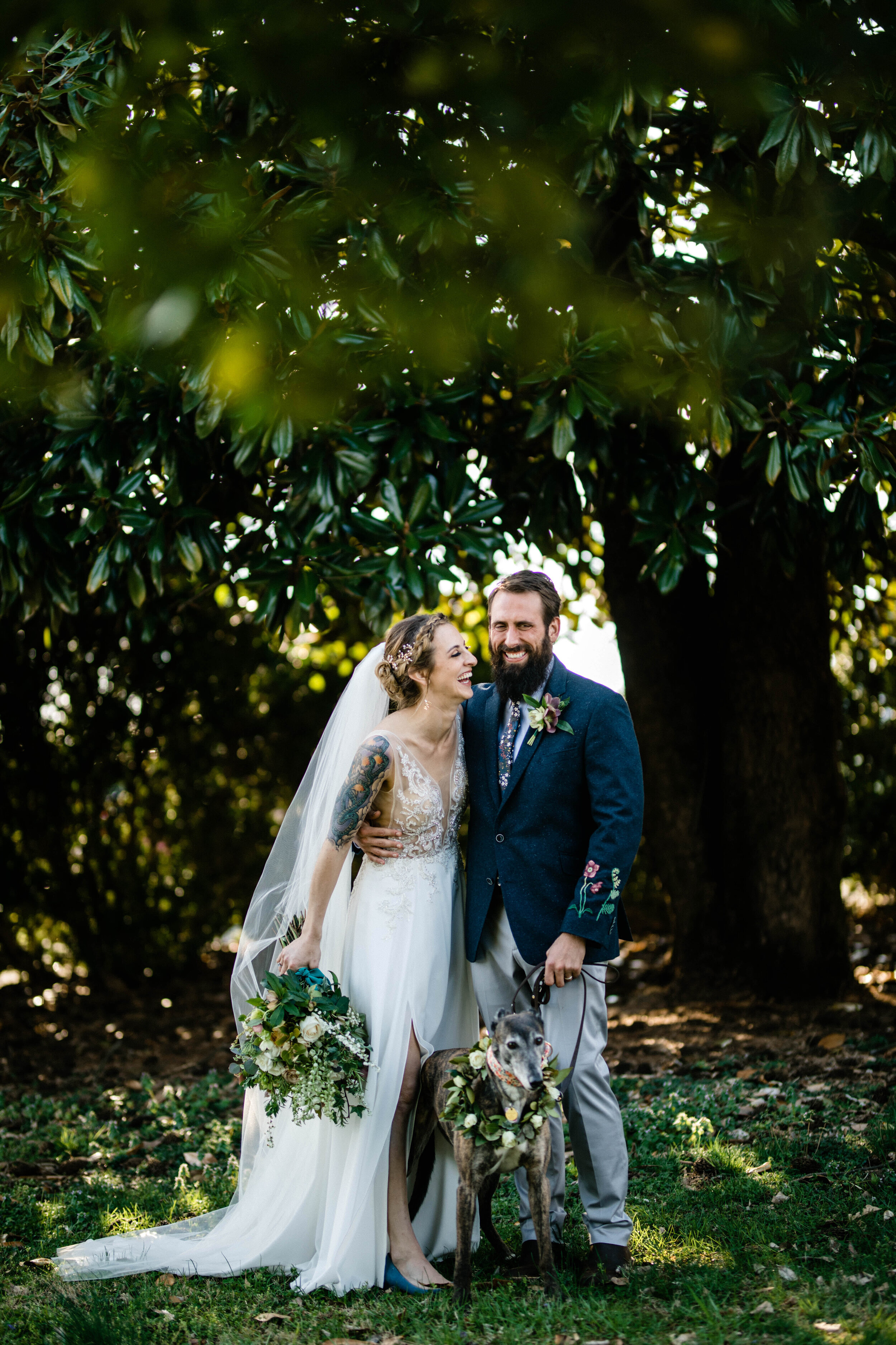 Bride and groom smiling together holding flowers with their dog in RVA Shawnee Custalow Queer Wedding Photographer