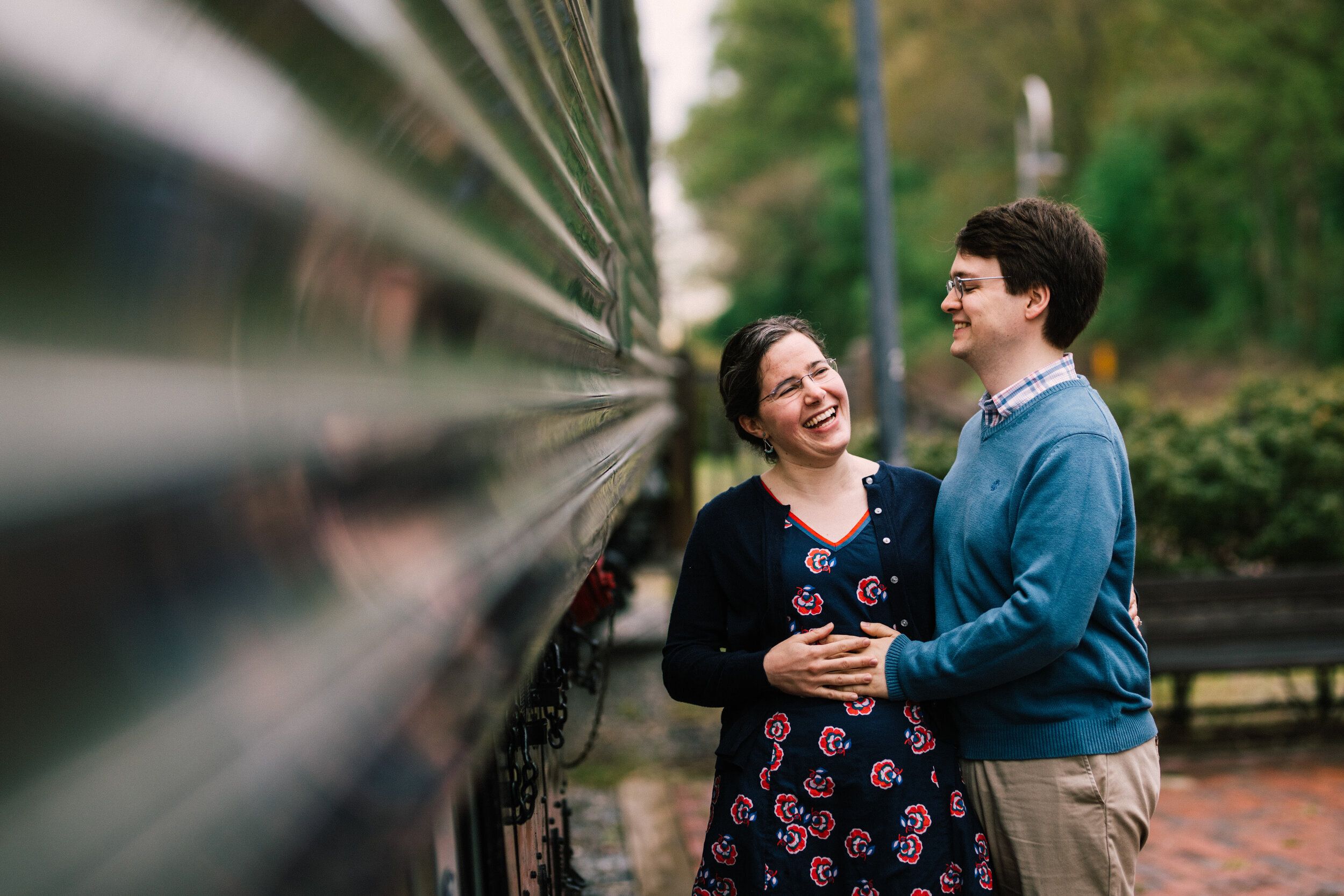 Expecting couple posing holding the mothers stomach next to a train car Shawnee Custalow DC Wedding Photographer