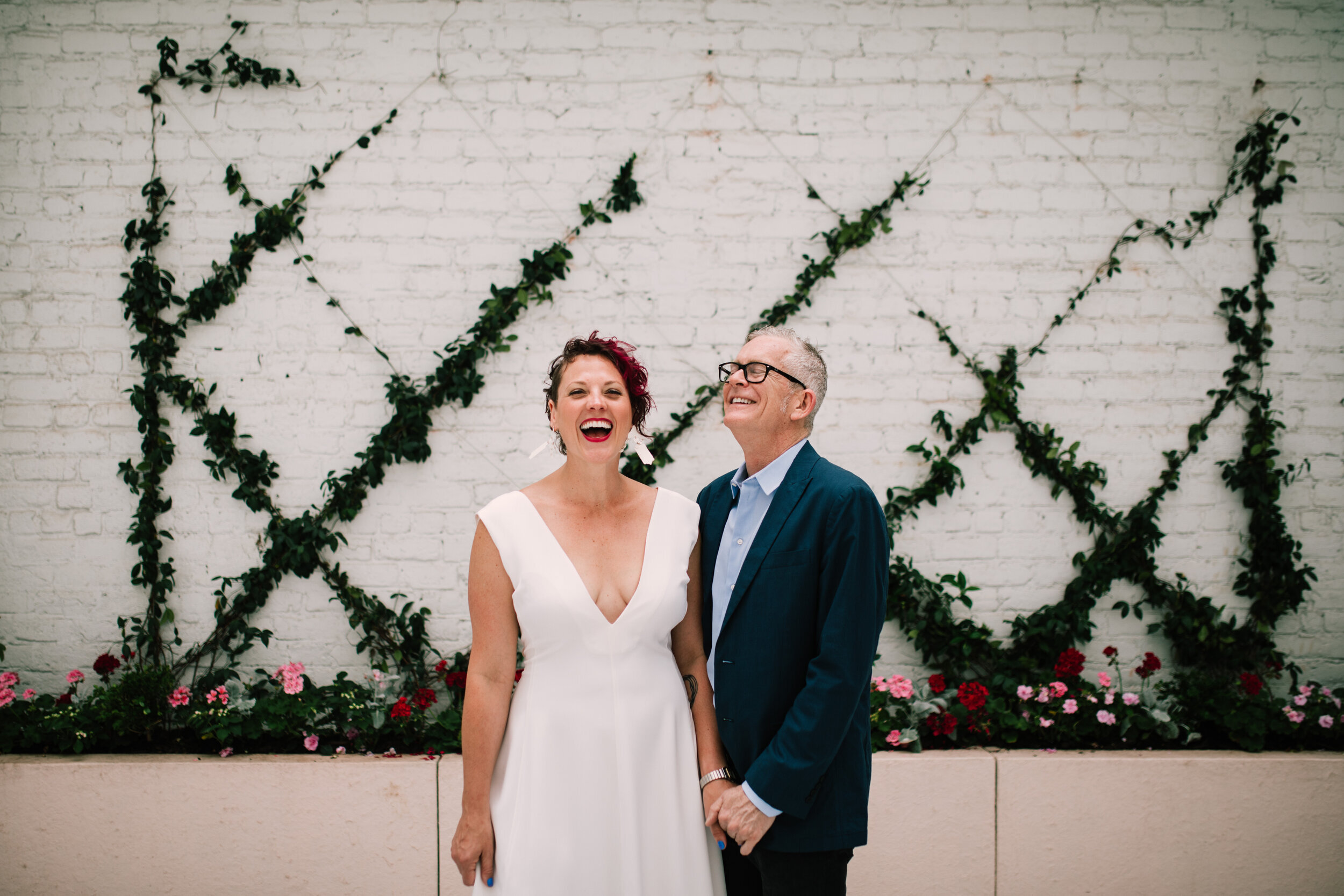 Bride and groom holding hands and smiling in the Quirk Hotel courtyard RVA Shawnee Custalow Queer Wedding Photographer