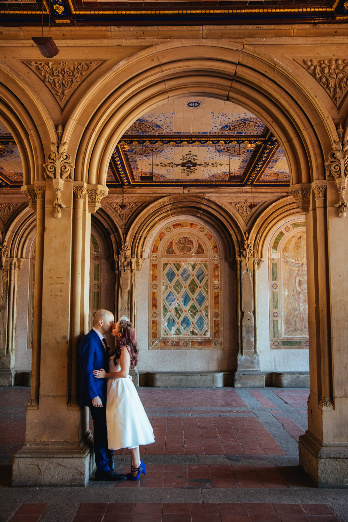 Newlywed couple kissing against a column under unique mosaic architecture Shawnee Custalow Queer Wedding Photographer