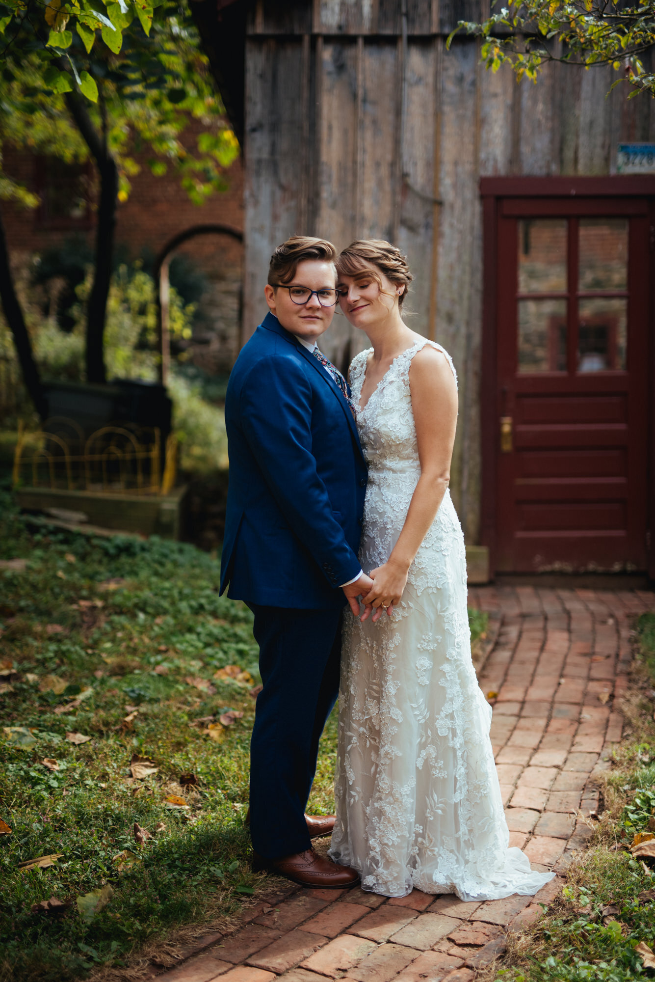 Newlywed LGBTQ couple holding hands and posing outside in Richmond VA Shawnee Custalow Queer Wedding Photographer