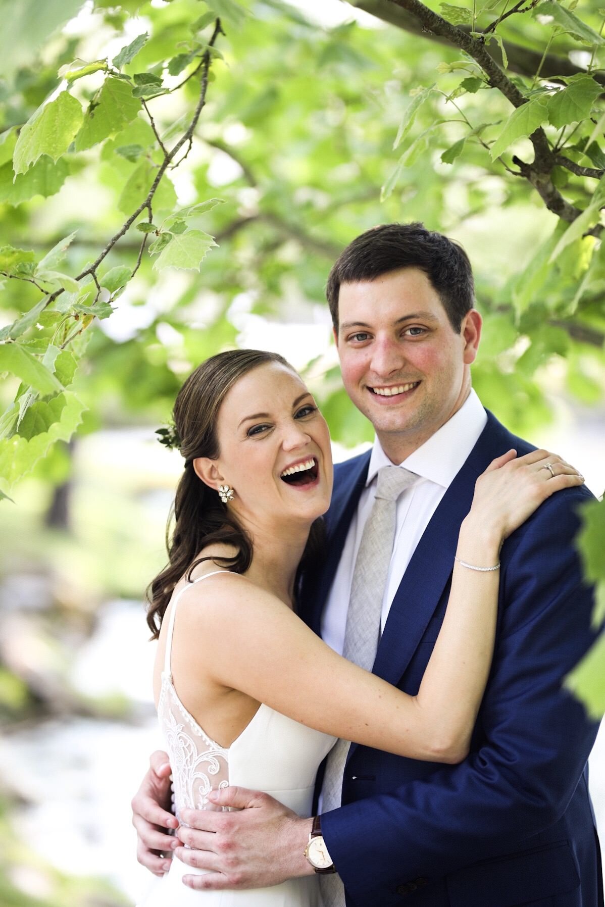 Bride and groom smiling and embracing under a tree in Richmond VA Shawnee Custalow Queer Wedding Photographer