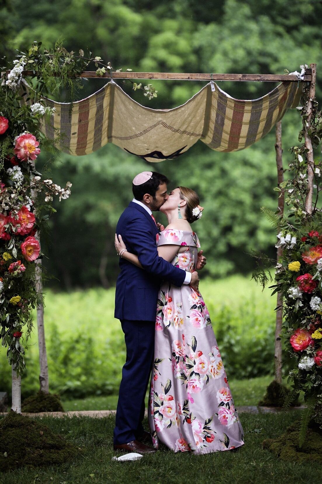 Multicultural newlywed couple kissing under a chuppah in Richmond VA Shawnee Custalow Queer Wedding Photographer