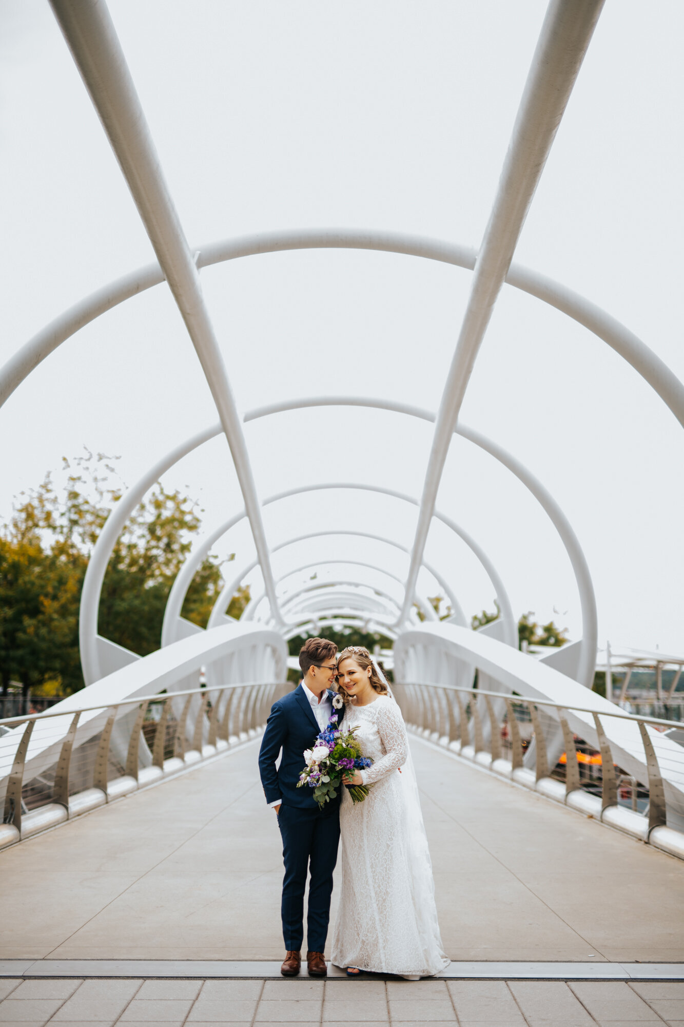 LGBTQ couple in wedding attire posing on a bridge in Washington DC Shawnee Custalow Queer Wedding Photographer