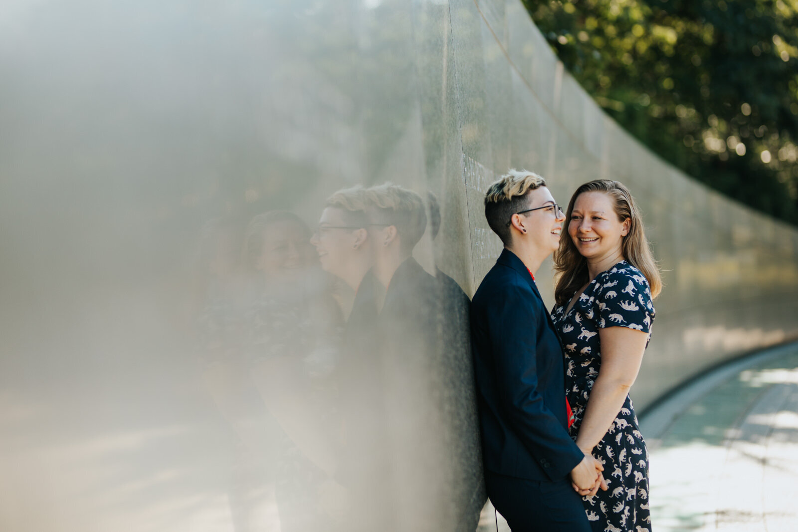 LGBTQ couple posing together on a smooth concrete wall in DC Shawnee Custalow Queer Wedding Photographer