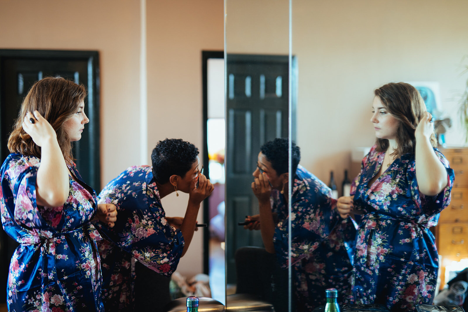 Bridesmaids in matching robes doing their make up and hair in Brooklyn Shawnee Custalow Queer Wedding Photographer