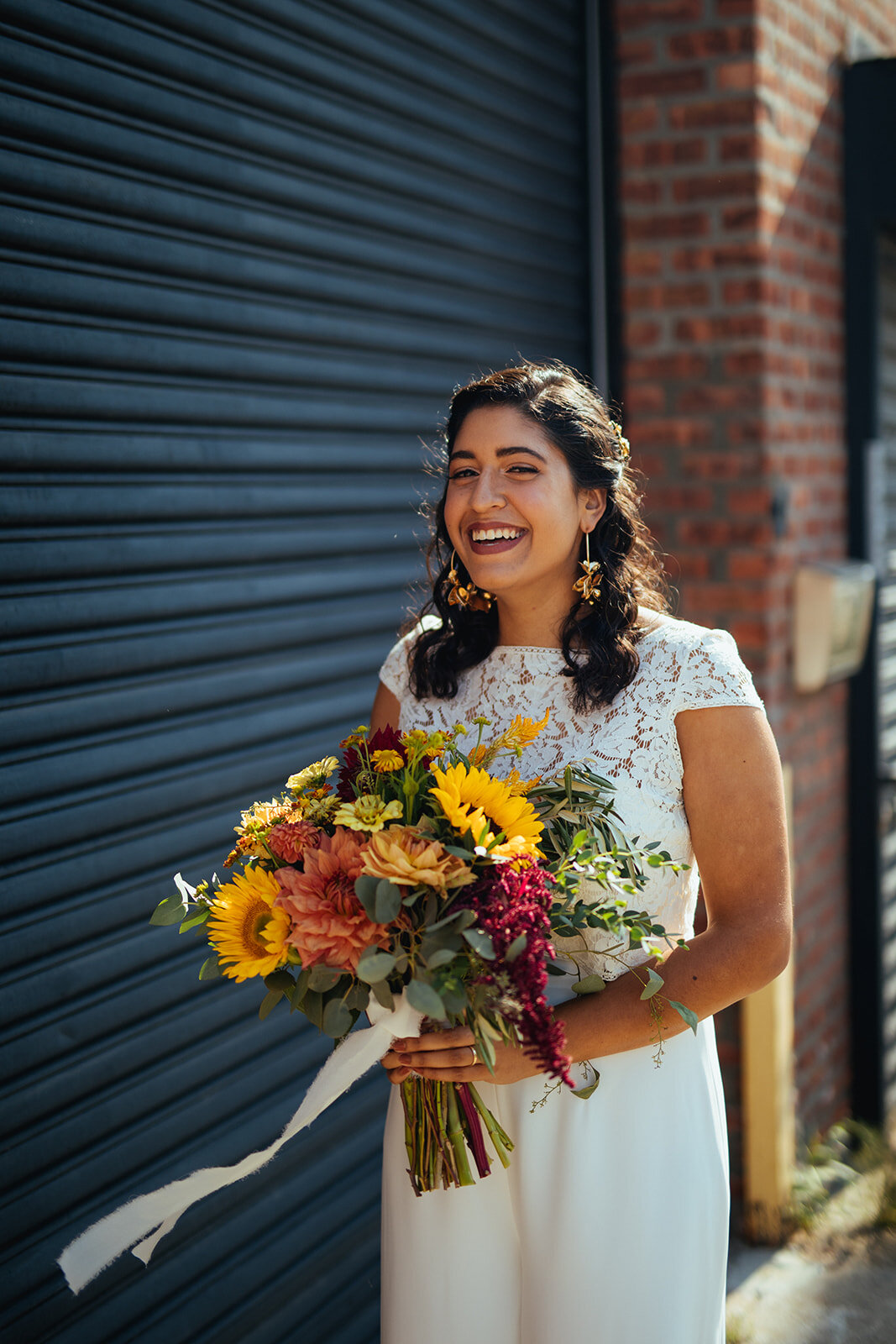 Portrait of bride smiling with orange and yellow bouquet in Brooklyn NY Shawnee Custalow Queer Wedding Photographer