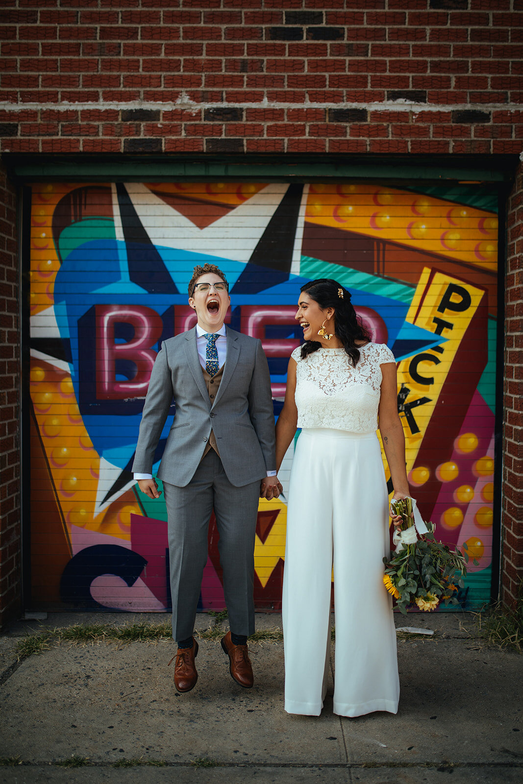 Future spouse jumping and holding hands with their bride in Brooklyn Shawnee Custalow Queer Wedding Photographer