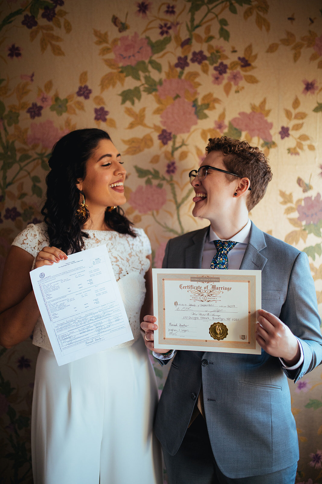 LGBTQ newlyweds holding marriage paperwork and smiling at Marlow Events Brooklyn Shawnee Custalow Queer Wedding Photographer