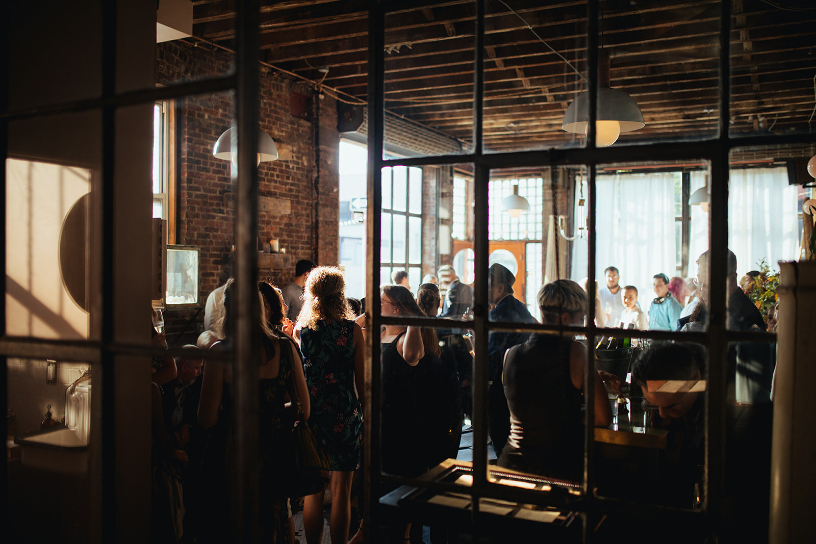 Wedding guests gathered inside Marlow Events in Red Hook Brooklyn Shawnee Custalow Queer Wedding Photographer