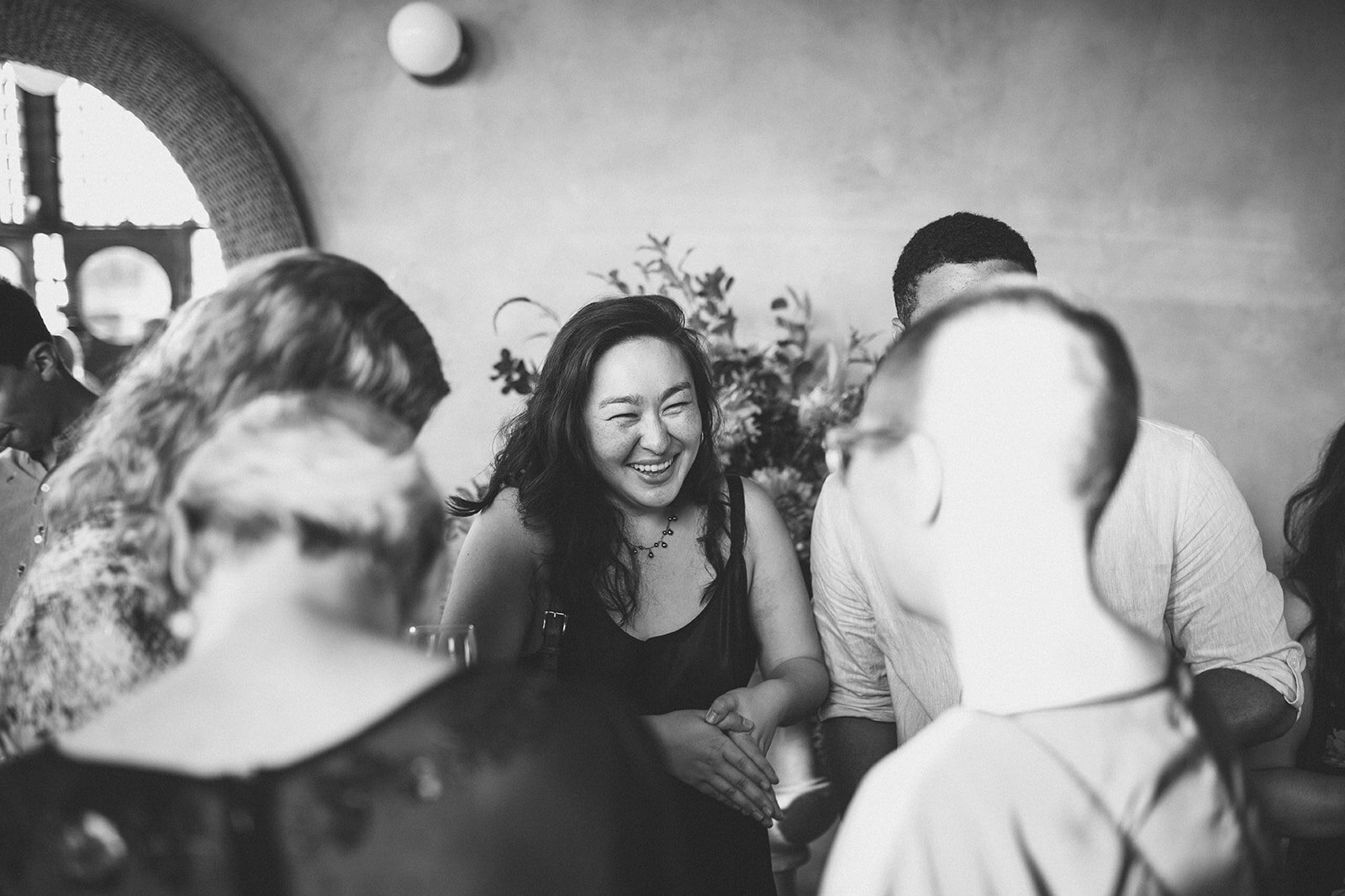 Wedding guests laughing at reception Marlow Events Red Hook Brooklyn Shawnee Custalow Queer Wedding Photographer