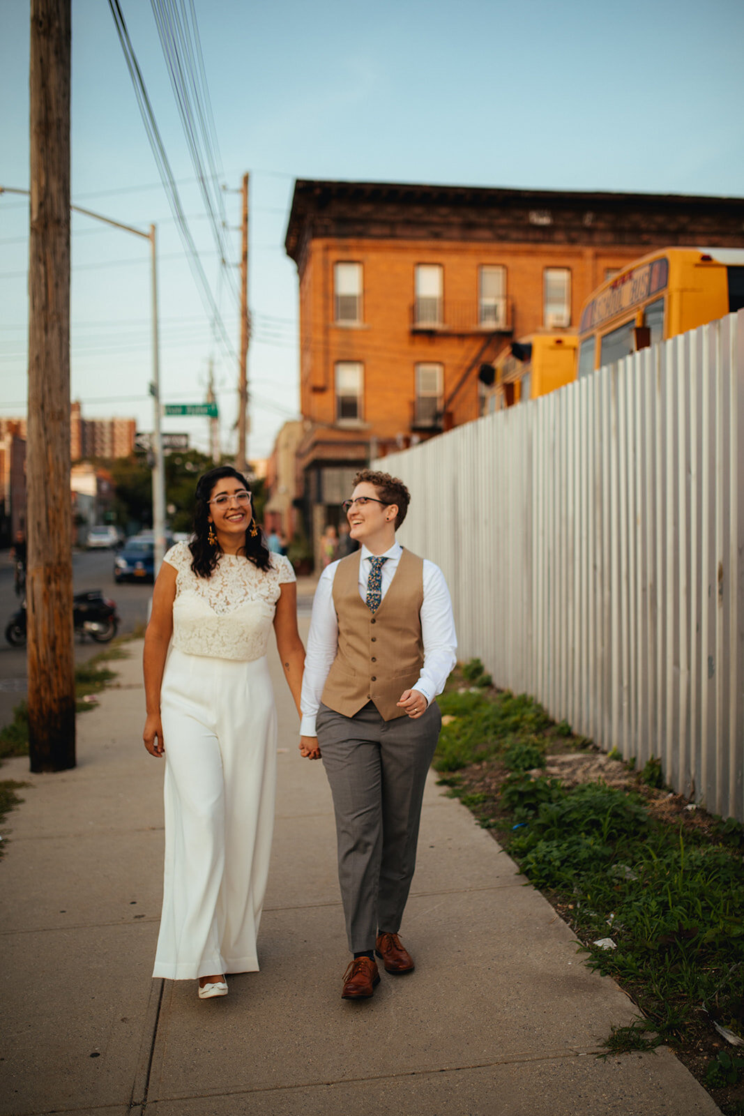 Newlywed LGBTQ couple holding hands walking on a sidewalk in Red Hook Brooklyn Shawnee Custalow Queer Wedding Photographer