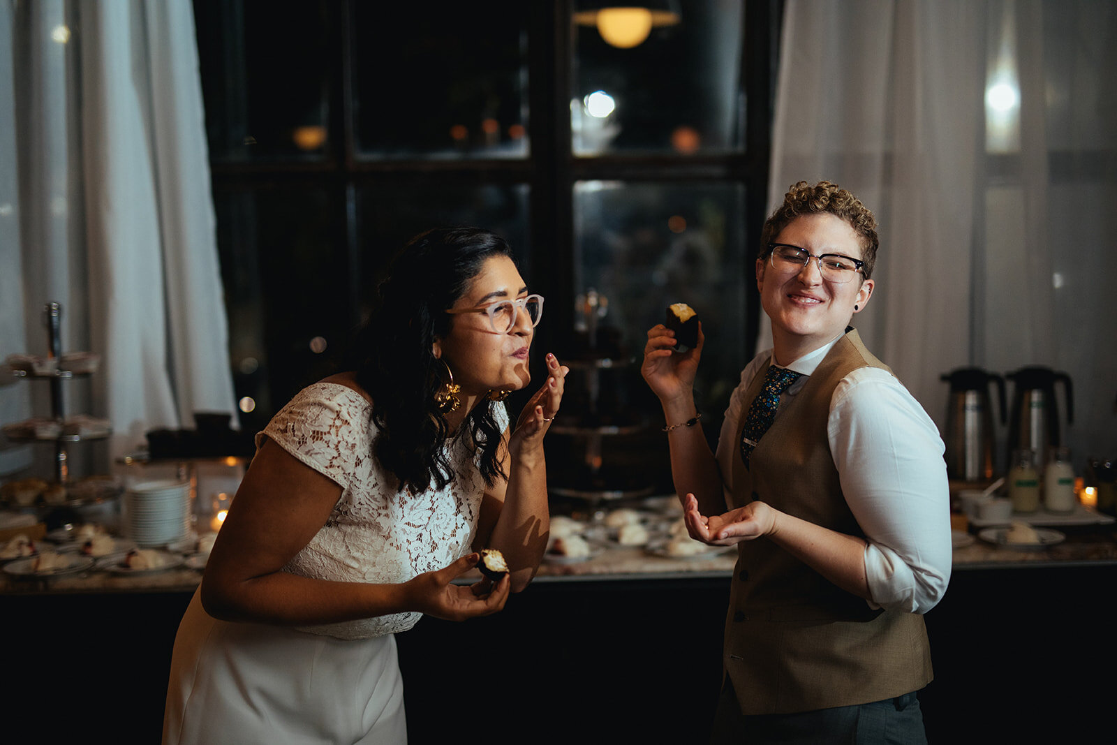Newlyweds laughing while eating cake at Marlow Events Red Hook Brooklyn Shawnee Custalow Queer Wedding Photographer