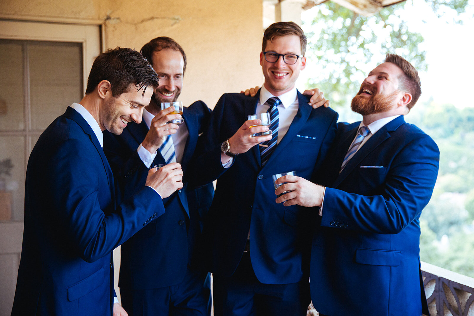 Groomsmen drinking in matching blue suits in Los Angeles Shawnee Custalow Queer Wedding Photography