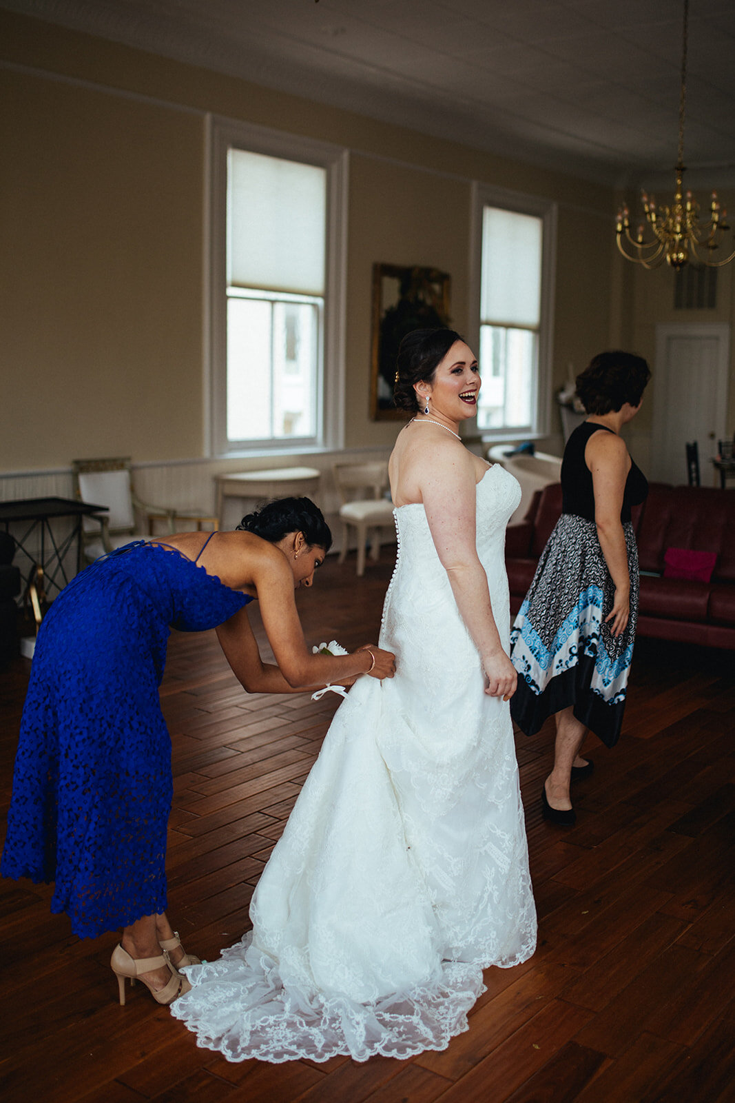 Bridesmaid helping bride button wedding dress in Alexandria VA Shawnee Custalow Queer Wedding Photography