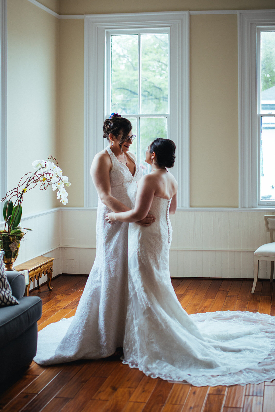 Two brides smiling together before wedding at Torpedo Factory Alexandria VA Shawnee Custalow Queer Wedding Photography