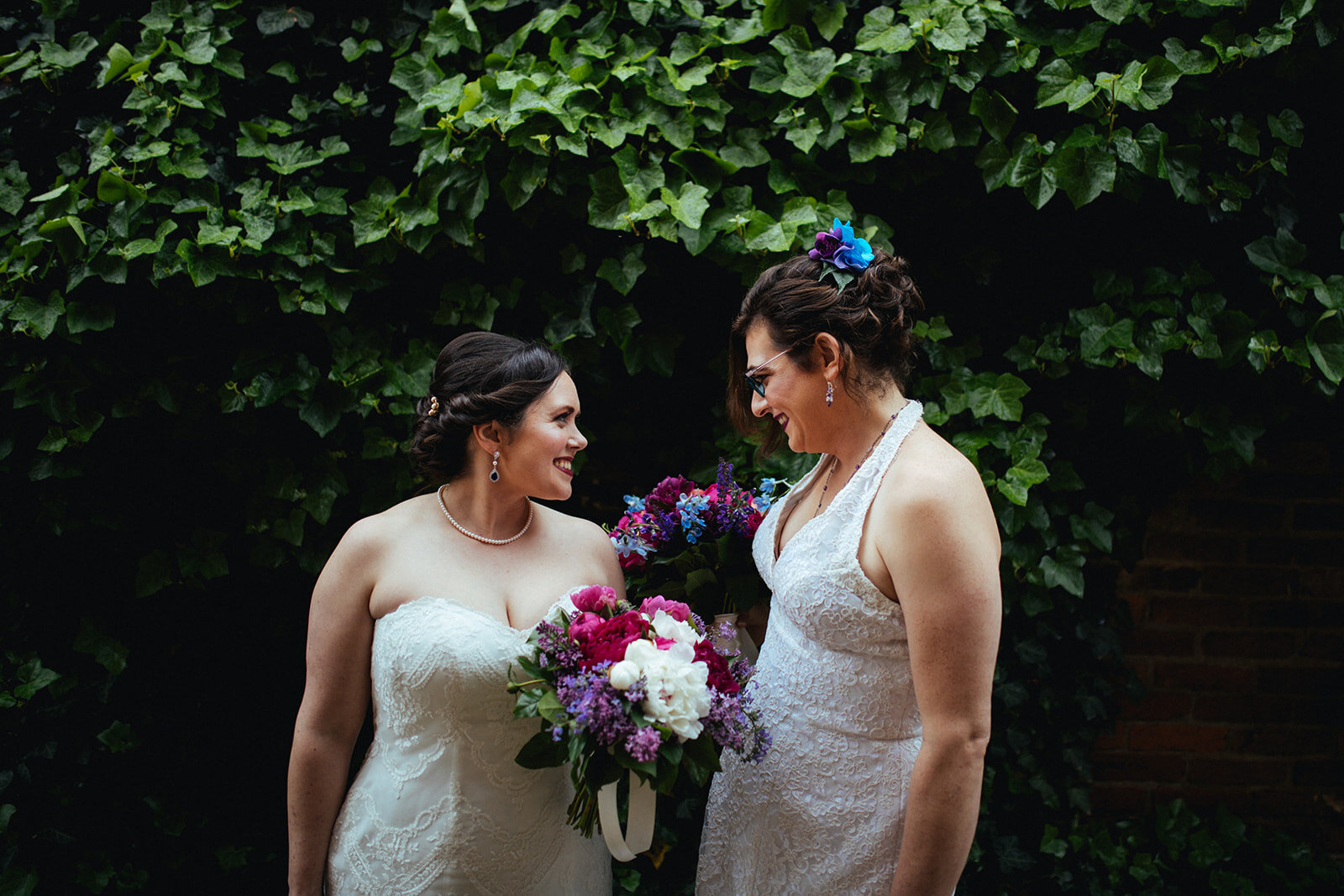 Newlywed brides smiling with bouquets in Alexandria VA Shawnee Custalow Queer Wedding Photographer