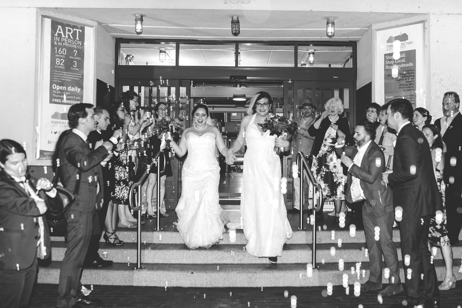 Newly married LGBTQ brides exiting through a shower of bubbles at Torpedo Factory Alexandria VA Shawnee Custalow