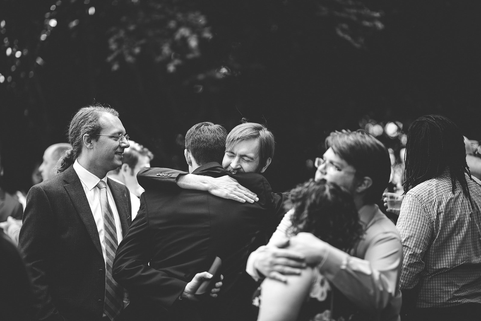 Guests hugging at backyard Atlanta reception Shawnee Custalow Queer Wedding Photographer