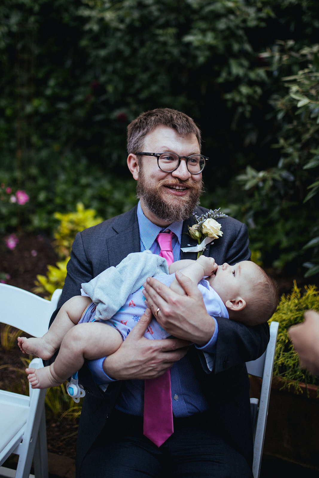 Newlywed groom holding a guests baby in Atlanta GA Shawnee Custalow Queer Wedding Photographer