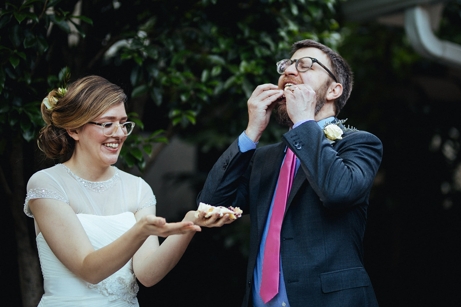 Bride holding cake while groom eats it in Atlanta GA Shawnee Custalow Queer Wedding Photographer