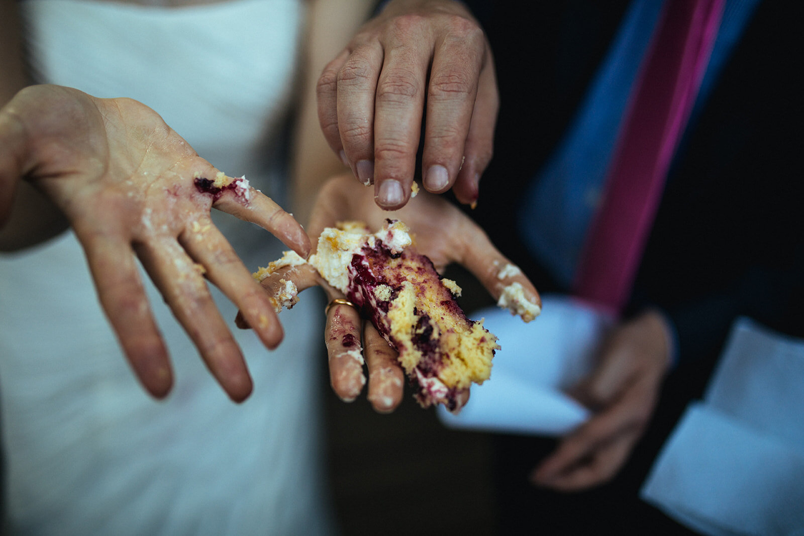Bride and grooms hands covered in cake in ATL Shawnee Custalow Queer Wedding Photographer
