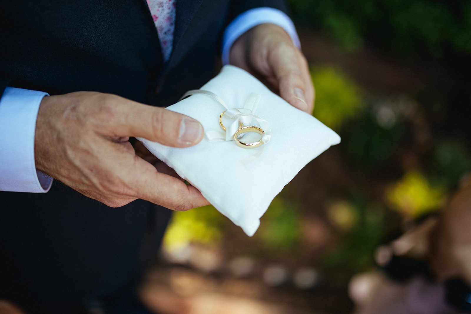 Wedding rings being carried on a pillow with ribbon in Atlanta GA Shawnee Custalow Queer Wedding Photographer