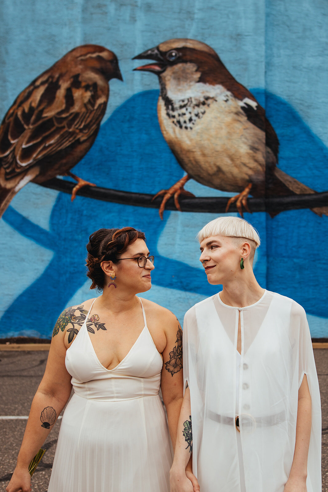 LGBTQ newlyweds smiling at each other under a mural in Philly Shawnee Custalow Queer Wedding photography