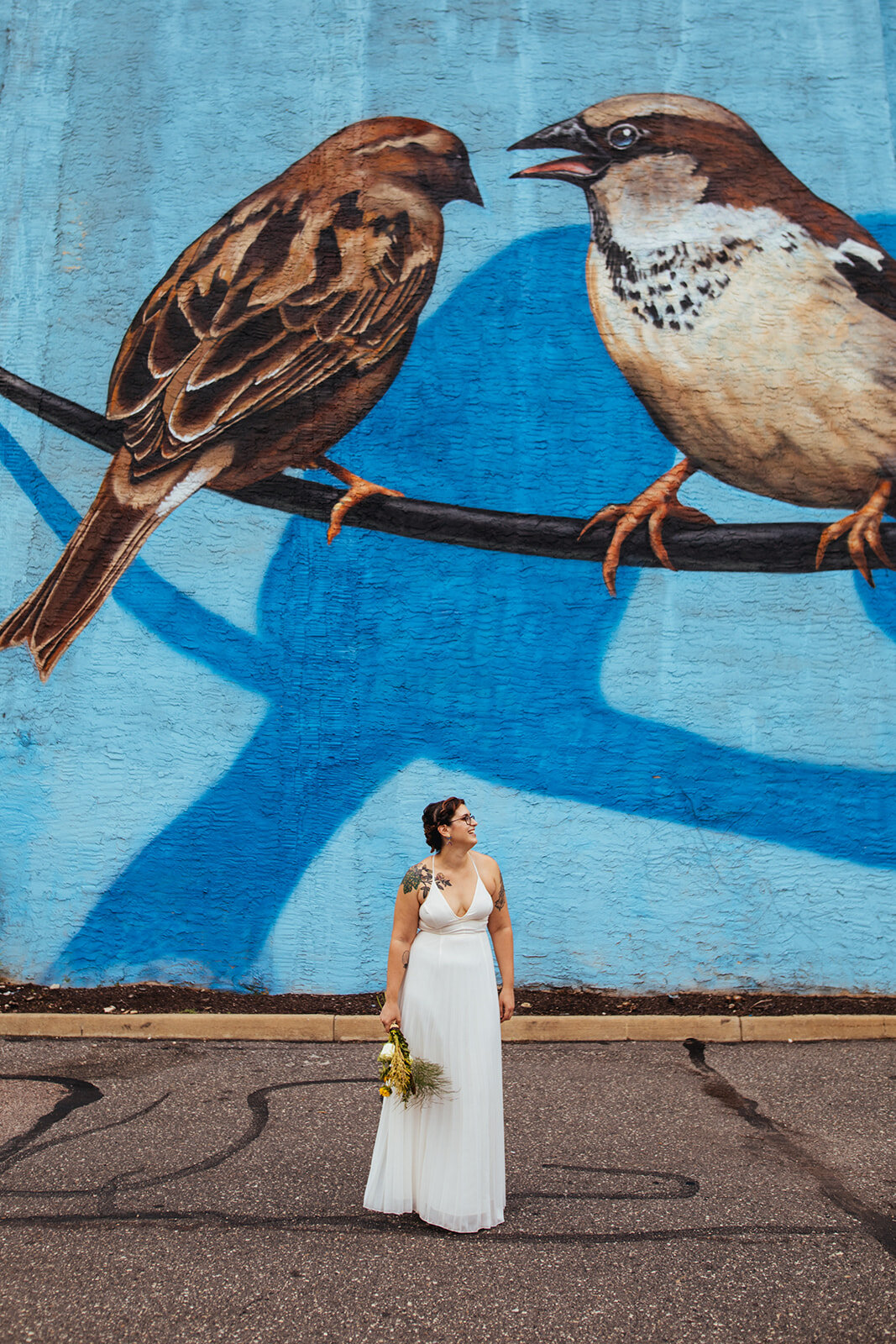 Bride standing in front of a bird mural in Philadelphia PA Shawnee Custalow Queer Wedding Photography