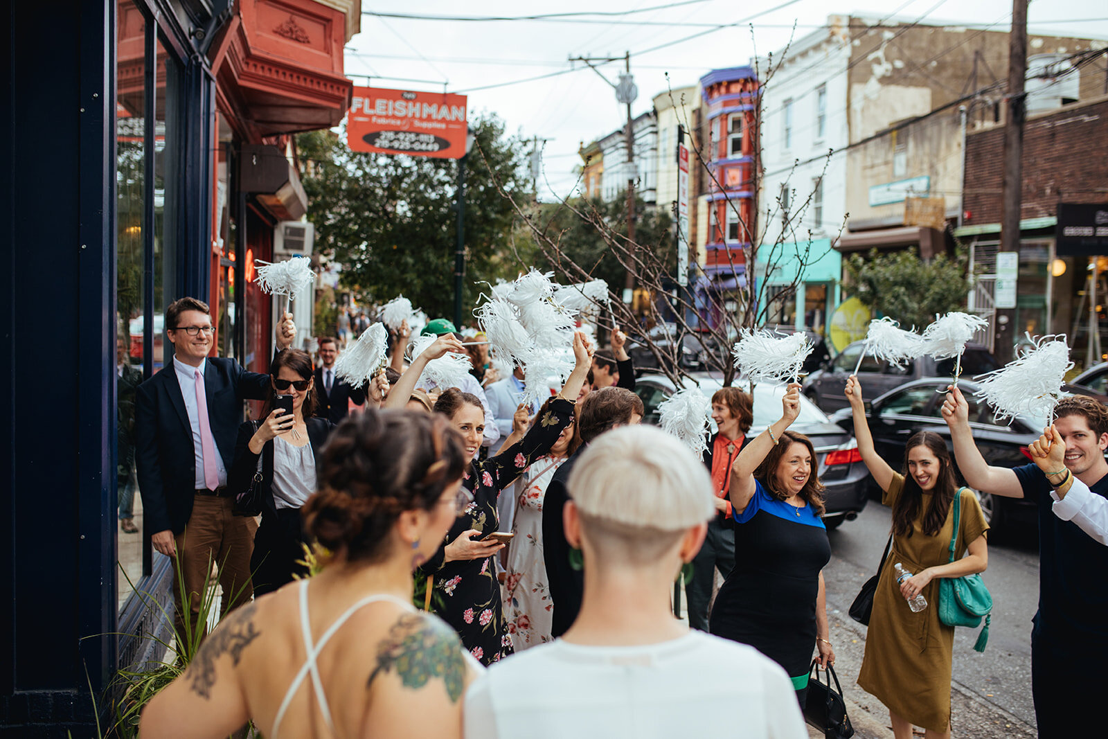 Newlyweds watching theirs guests waive pompoms on the street in Philadelphia Shawnee Custalow photography