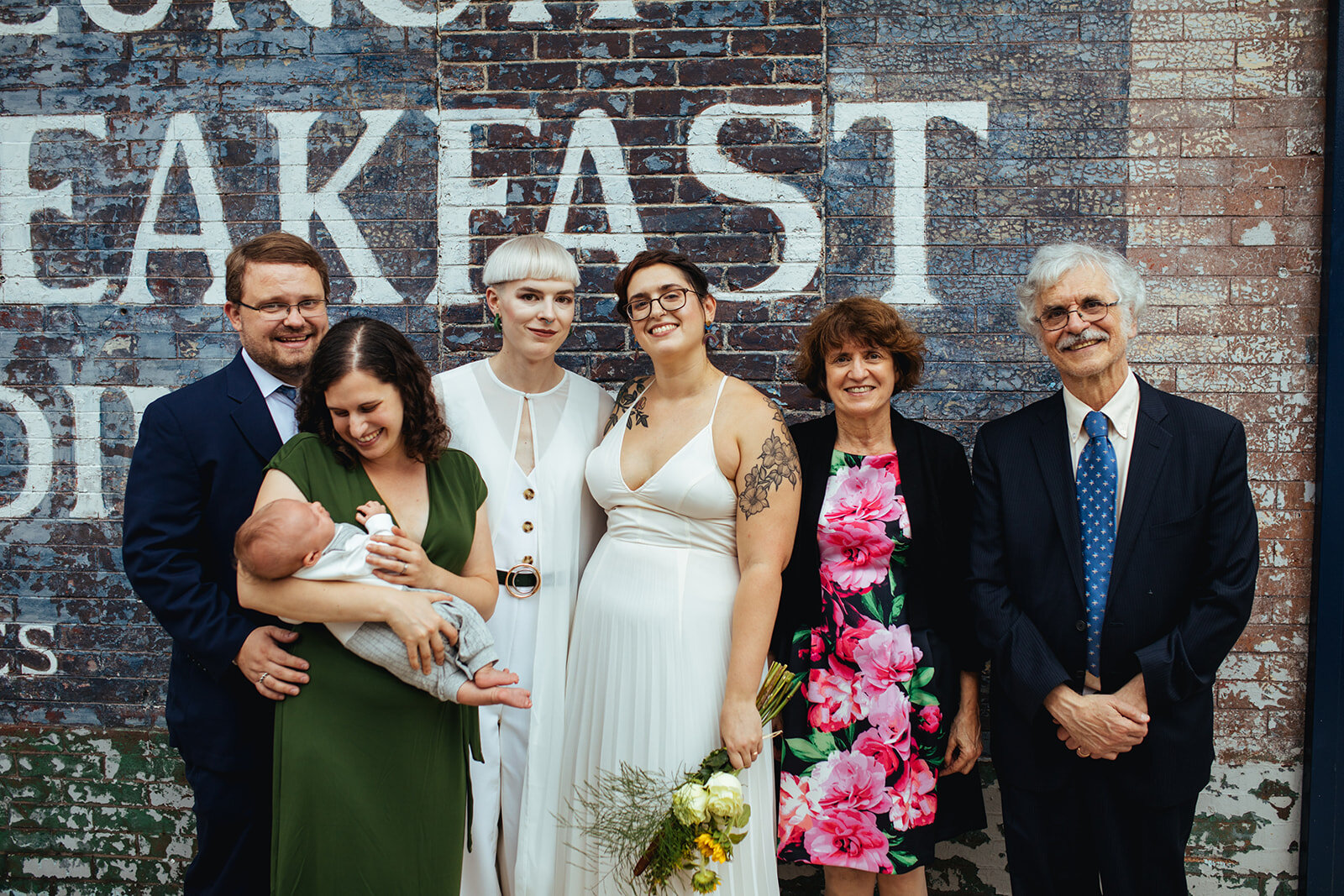 Newlyweds posing with family by a mural in Philadelphia Shawnee Custalow Queer Wedding photography