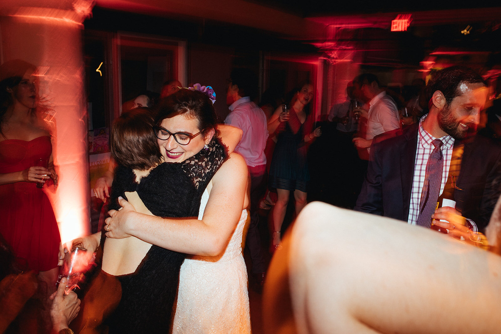 Bride and guest hugging at Torpedo Factory reception Alexandria VA Shawnee Custalow Queer Wedding Photography