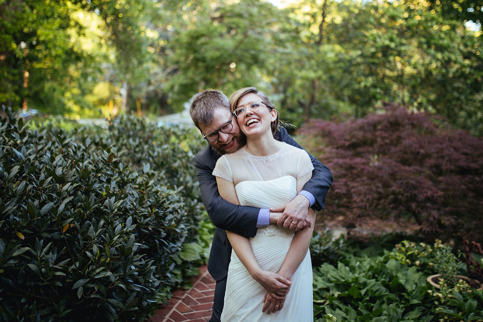 Groom hugging bride from behind in their backyard in Atlanta GA Shawnee Custalow Queer Wedding Photographer