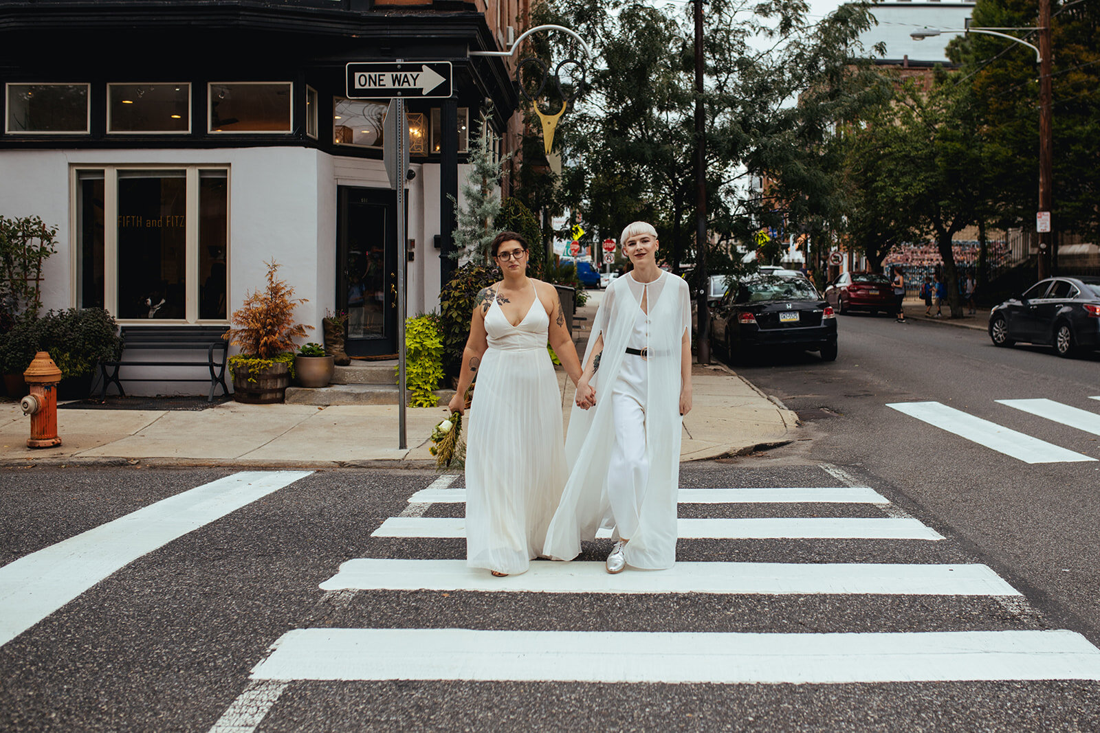 LGBTQ couple in white wedding attire on a cross walk in Philly PA Shawnee Custalow Photography