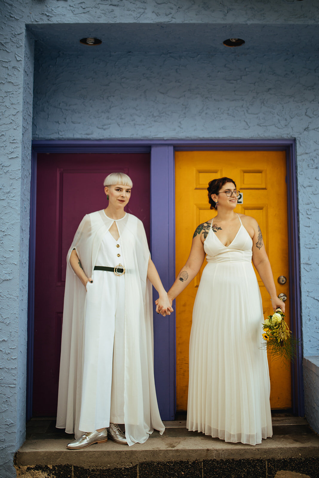 LGBTQ couple holding hands by brightly colored doors in Philly Shawnee Custalow Queer Wedding Photography