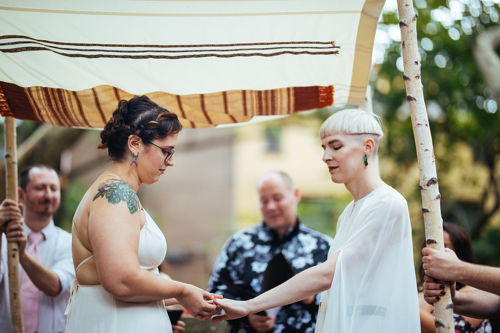 LGBTQ couple exchanging rings under a chuppah in Philly Shawnee Custalow Queer Wedding photography