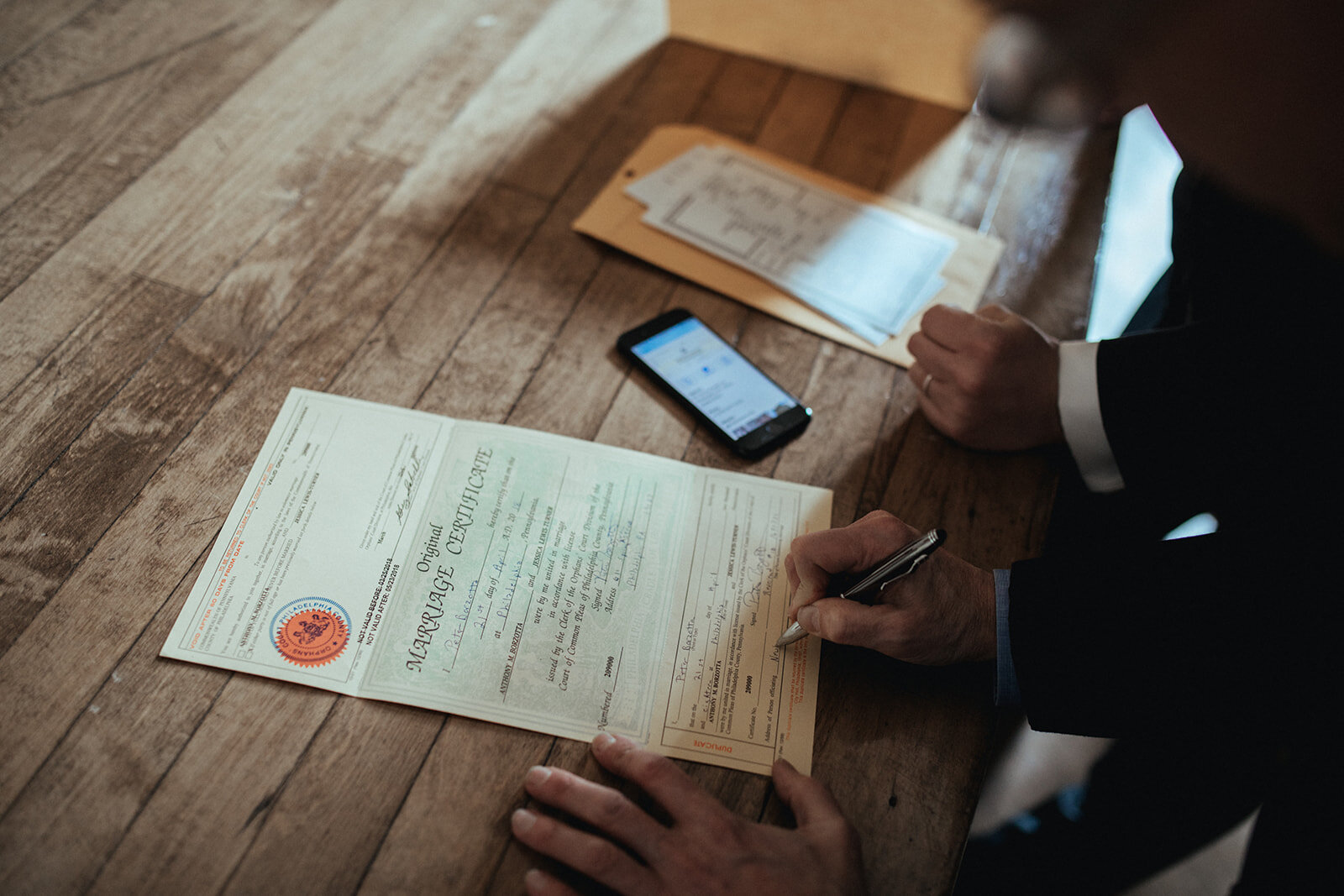 Hands signing a marriage certificate at German Society of PA Shawnee Custalow LGBTQ wedding Photography