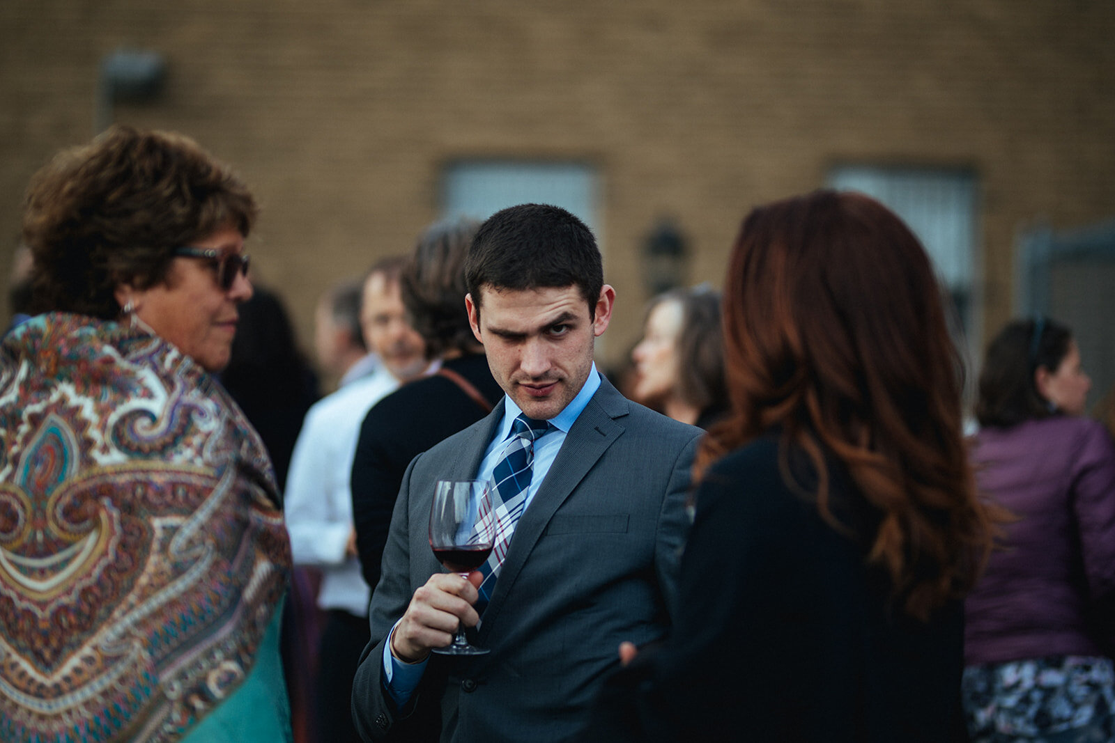 Man raising an eyebrow drinking wine at Philadelphia wedding reception PA Shawnee Custalow photo