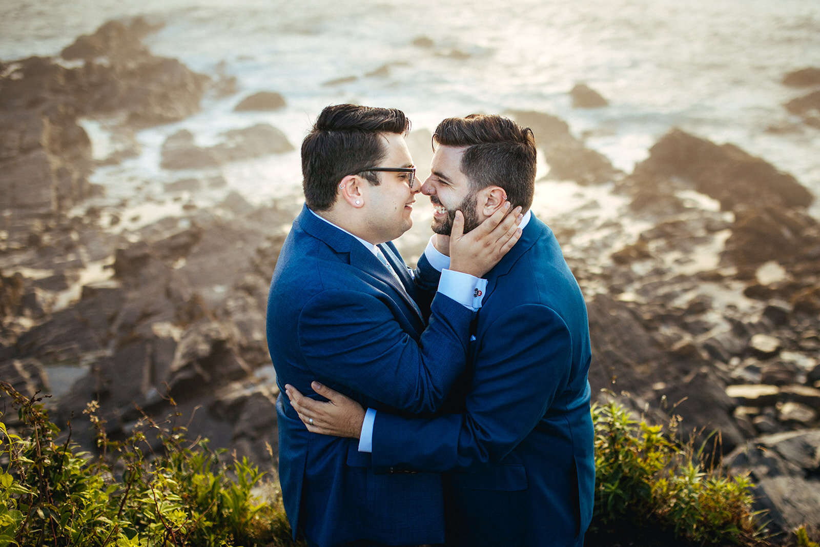 Grooms touching noses by the ocean on Peaks Island Portland ME Shawnee Custalow Queer wedding photography