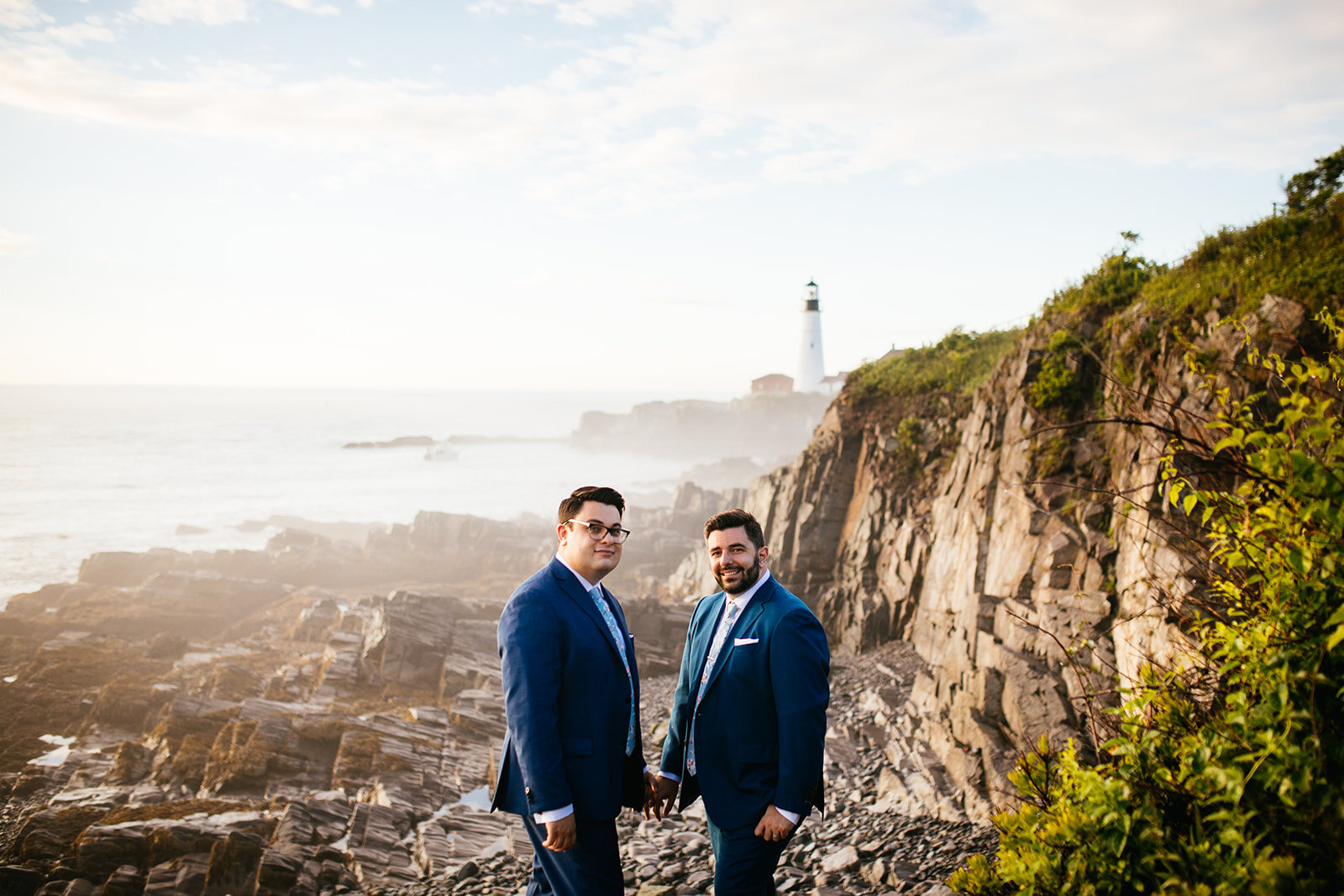 Two grooms holding hands by a light house on Peaks Island Portland ME Shawnee Custalow photography