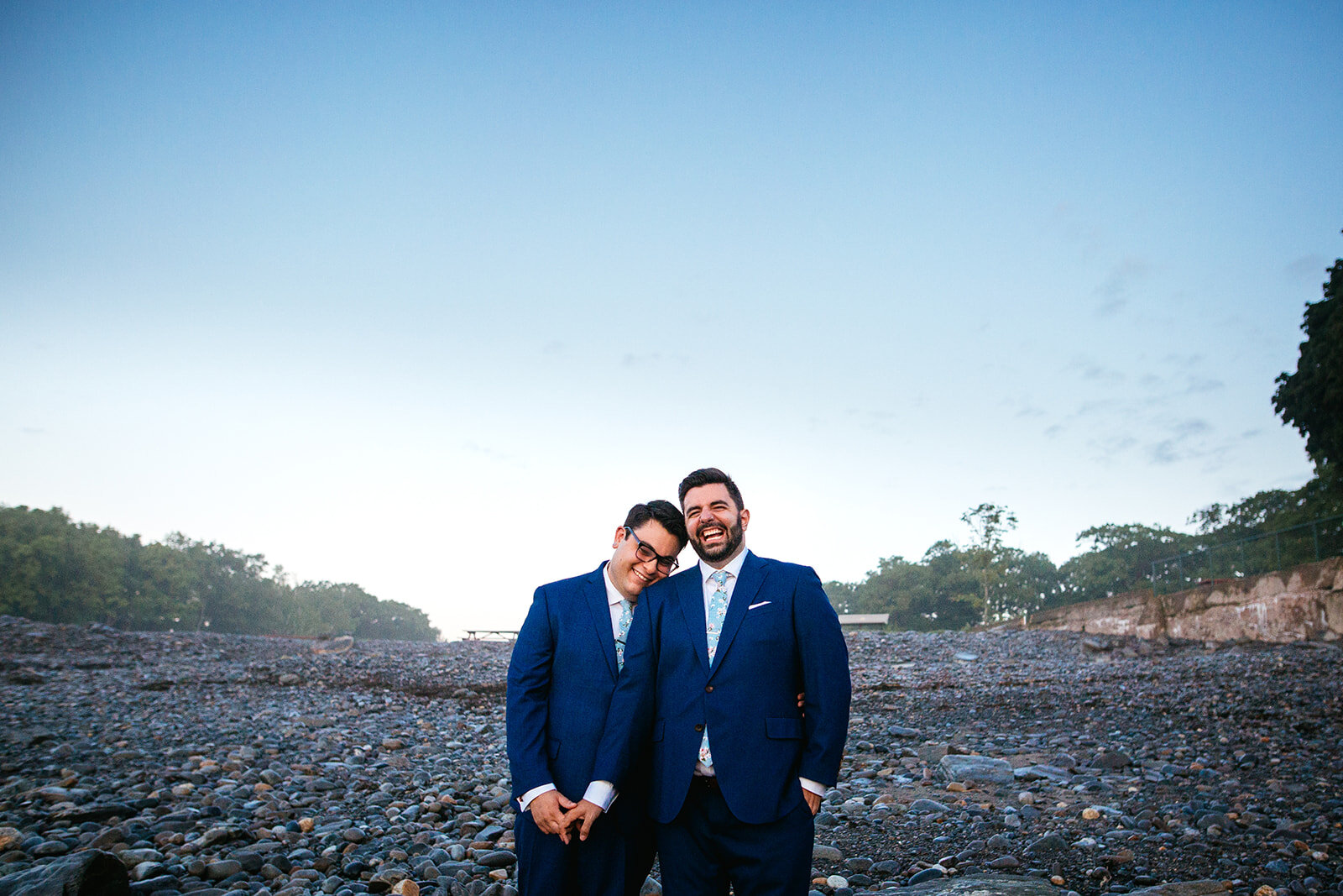LGBTQ couple laughing in matching suits on Peaks Island Portland ME Shawnee Custalow wedding photography
