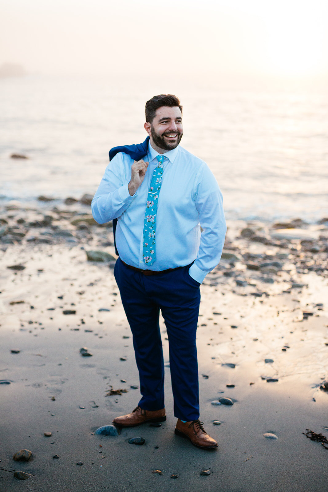 Portrait of groom holding suit jacket on the beach of Peaks Island Portland ME Shawnee Custalow wedding photography
