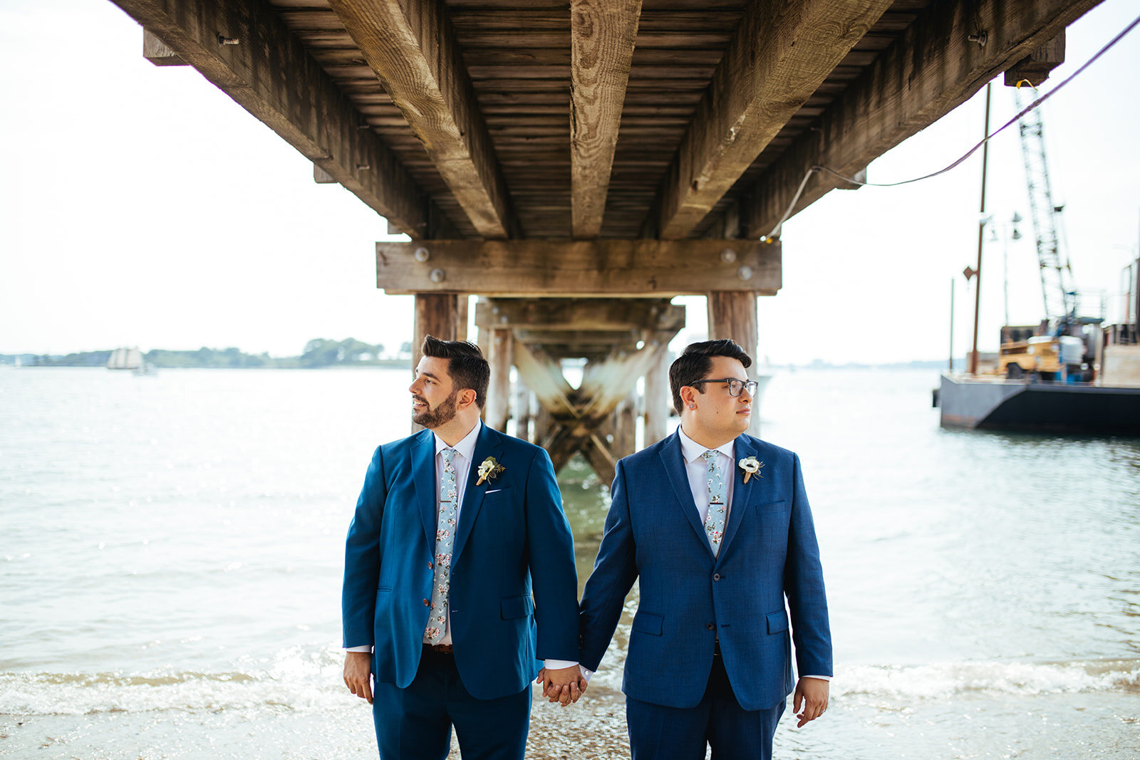 Grooms to be wed under pier in Portland ME Shawnee Custalow Queer wedding photography