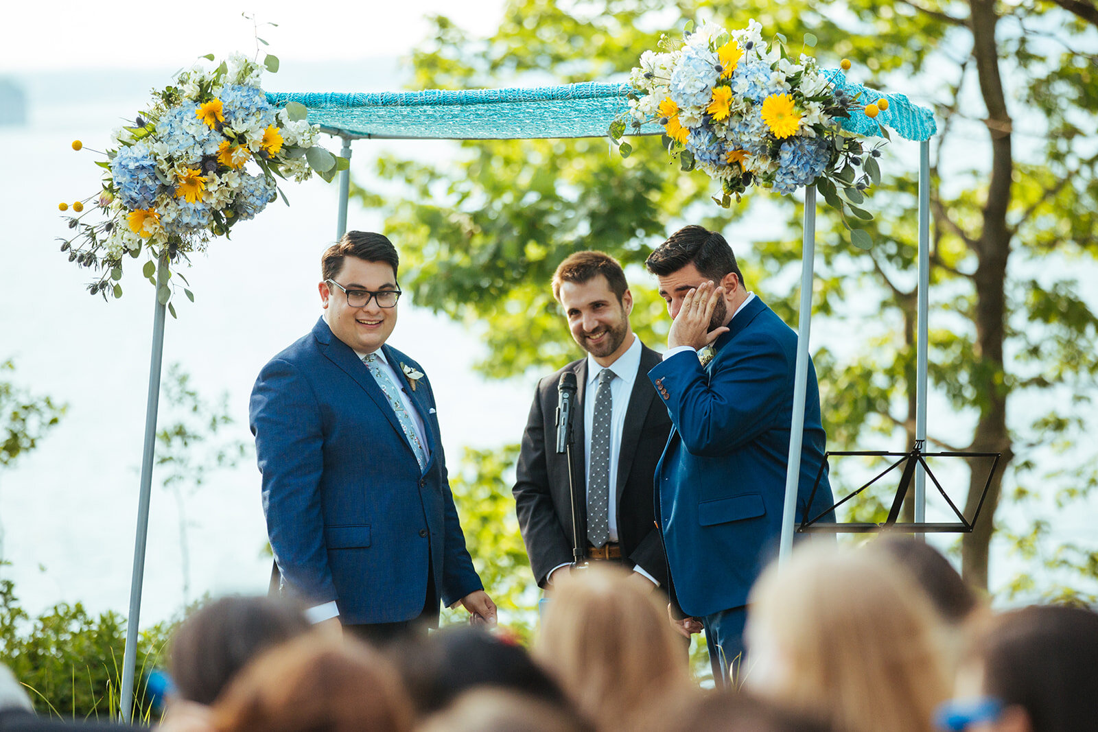 Grooms and officiant smiling at their guests in Portland ME Shawnee Custalow Queer wedding photography